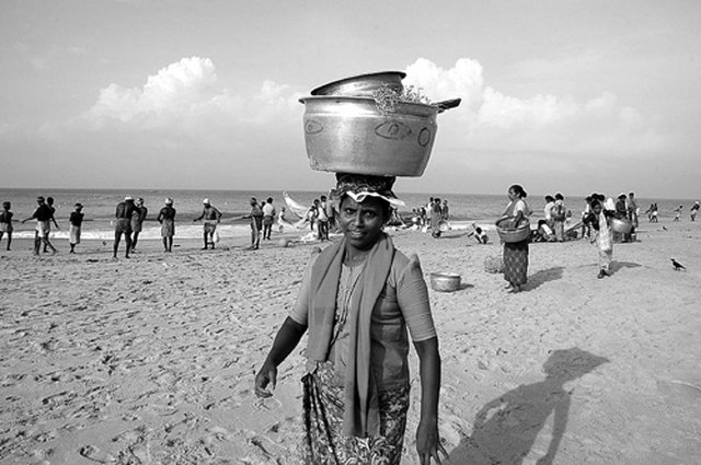 One of the fisherwomen, anticipating the arrival of newly caught fishes and other marine produce along Chowara beach in Kerala, India.